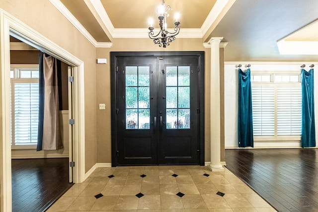 tiled entryway with french doors, ornamental molding, a chandelier, and ornate columns