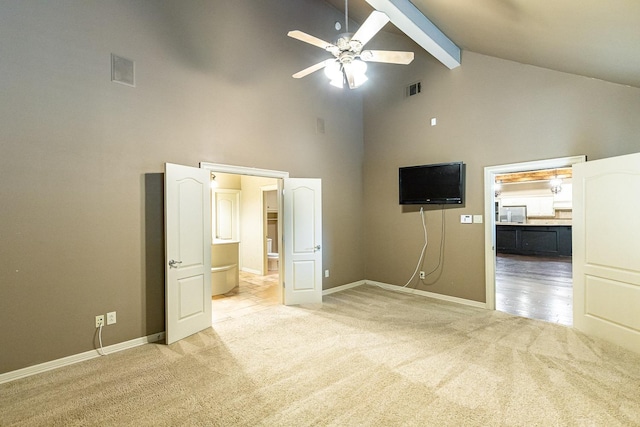 unfurnished bedroom with beamed ceiling, ceiling fan, light colored carpet, and high vaulted ceiling