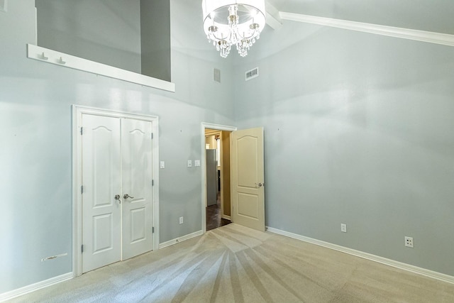 unfurnished bedroom featuring high vaulted ceiling, light carpet, an inviting chandelier, and a closet