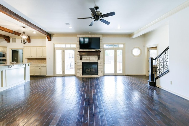 unfurnished living room with beamed ceiling, plenty of natural light, and dark wood-type flooring