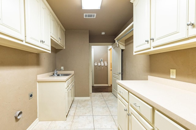 washroom with hookup for an electric dryer, sink, and light tile patterned floors