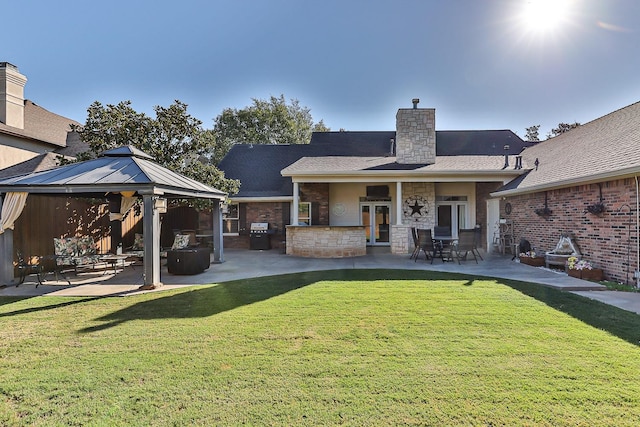 rear view of property featuring a gazebo, a lawn, and a patio