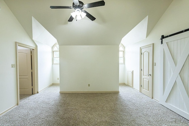 bonus room with lofted ceiling, light carpet, a barn door, and ceiling fan