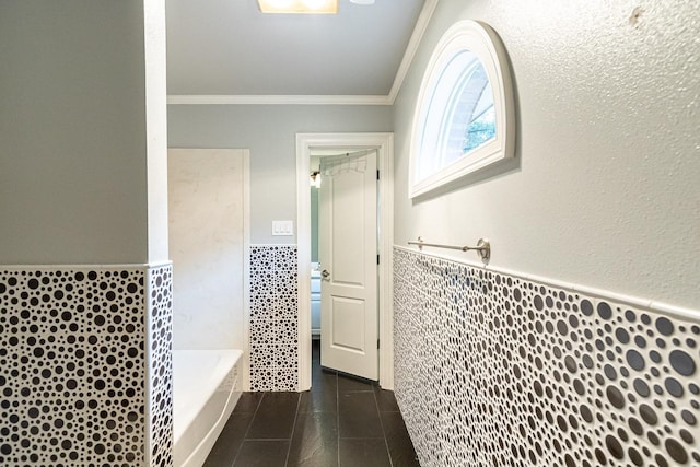 bathroom featuring crown molding, tile walls, and a tub