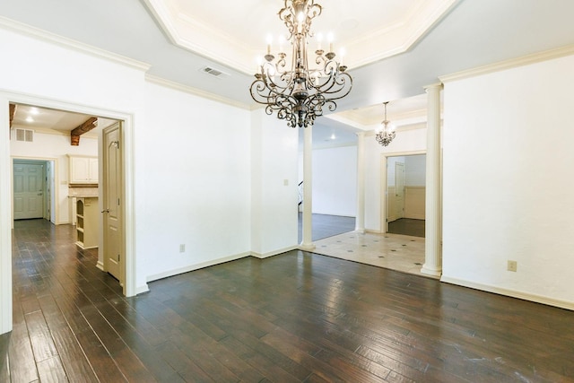 unfurnished room featuring an inviting chandelier, ornamental molding, a tray ceiling, and decorative columns