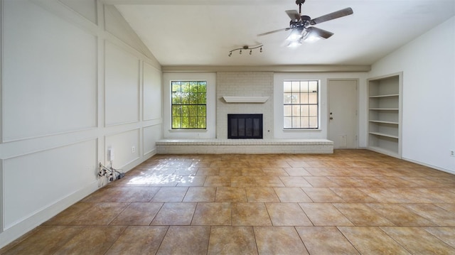 unfurnished living room featuring light tile patterned flooring, built in features, lofted ceiling, ceiling fan, and a brick fireplace