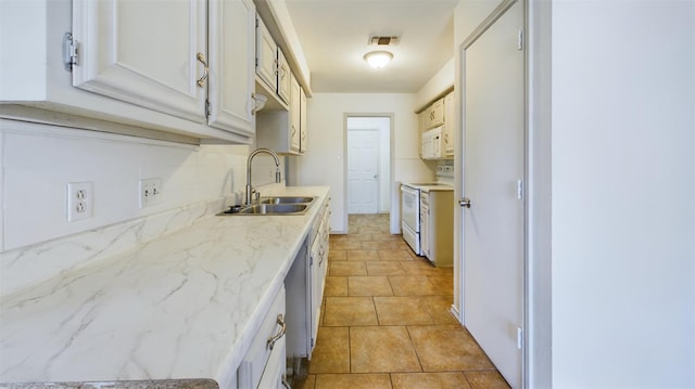 kitchen with tasteful backsplash, white cabinetry, sink, light tile patterned floors, and white appliances