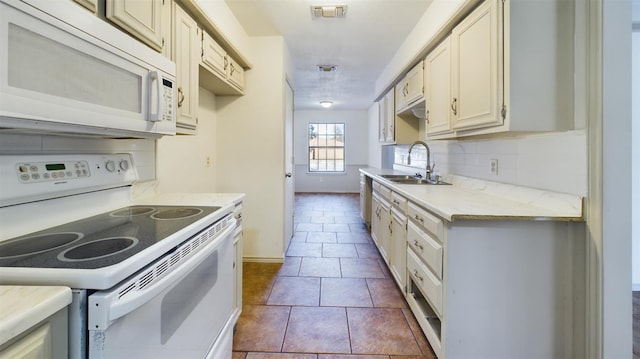 kitchen with sink, white appliances, dark tile patterned flooring, and backsplash