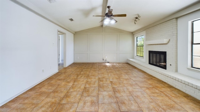 unfurnished living room featuring lofted ceiling with beams, a brick fireplace, light tile patterned floors, and ceiling fan