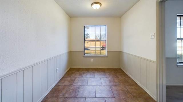 unfurnished room featuring a healthy amount of sunlight and dark tile patterned flooring