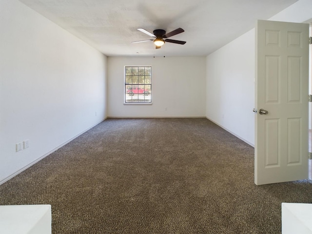 spare room featuring dark colored carpet and ceiling fan