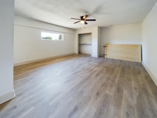 unfurnished bedroom with ceiling fan, wood-type flooring, and a closet