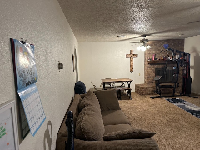 living room featuring ceiling fan, a stone fireplace, carpet floors, and a textured ceiling