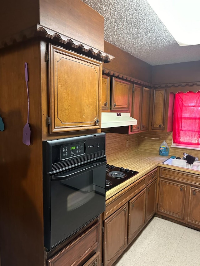 kitchen featuring sink, black electric stovetop, a textured ceiling, and wall oven