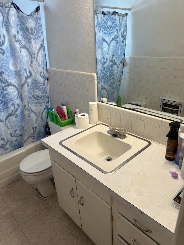 full bathroom featuring tile patterned floors, toilet, tile walls, vanity, and shower / bath combo with shower curtain