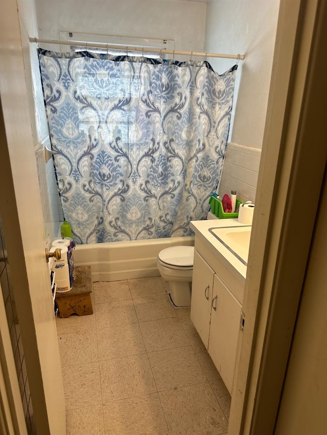 full bathroom with tile patterned floors, toilet, tile walls, vanity, and shower / bath combination with curtain