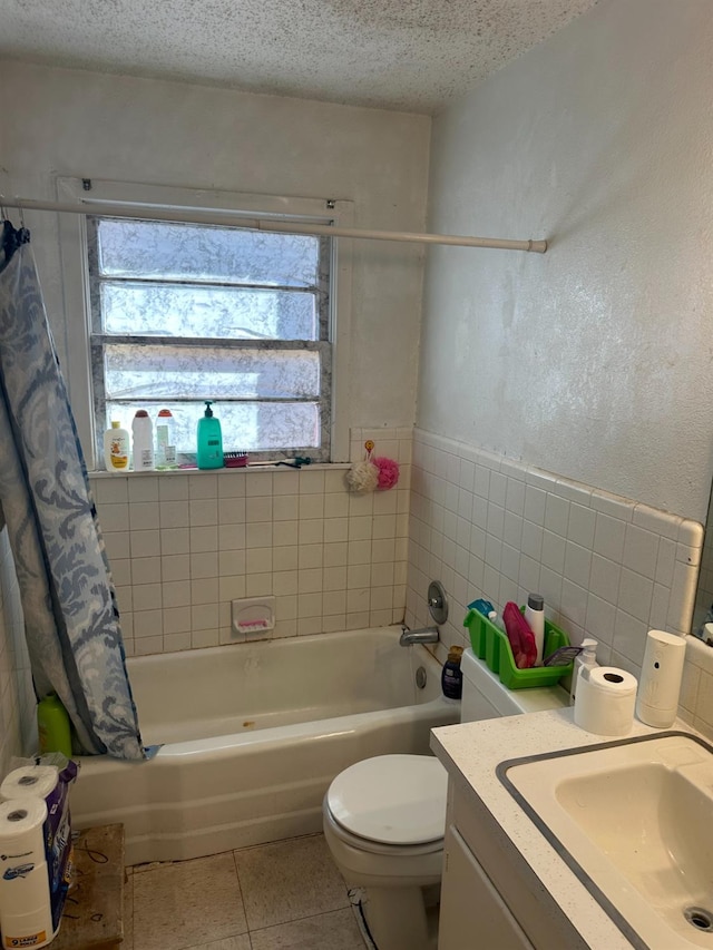 full bathroom with tile walls, vanity, a textured ceiling, tile patterned floors, and toilet