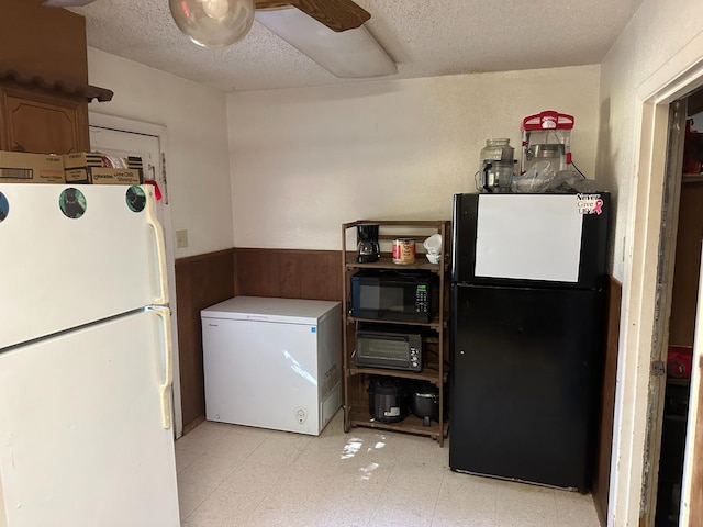 laundry area with ceiling fan, a textured ceiling, and wood walls