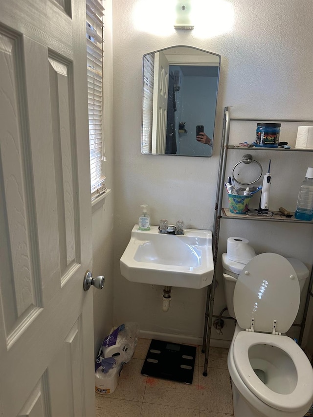 bathroom with toilet, tile patterned flooring, and sink