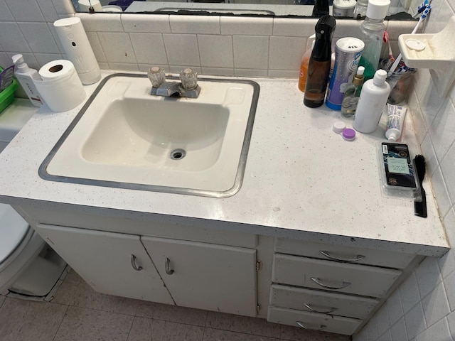 bathroom featuring vanity, toilet, tile walls, and backsplash