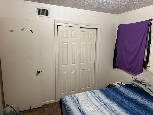 carpeted bedroom featuring a textured ceiling and a closet