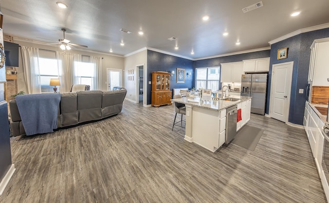 kitchen featuring white cabinetry, sink, a kitchen bar, stainless steel appliances, and a center island with sink