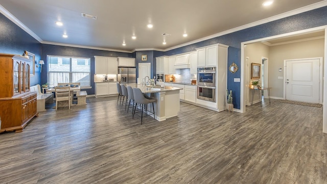 kitchen with an island with sink, a breakfast bar, white cabinets, and dark hardwood / wood-style floors