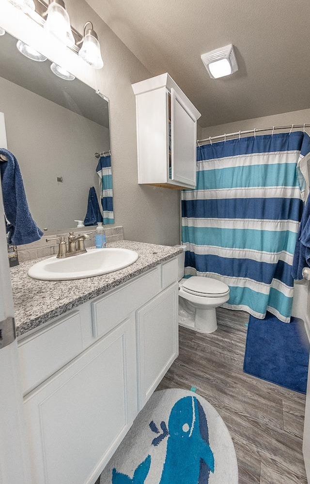 bathroom with toilet, a textured ceiling, vanity, a shower with shower curtain, and hardwood / wood-style floors