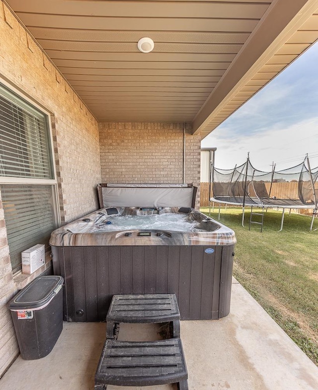 view of patio / terrace featuring a hot tub and a trampoline