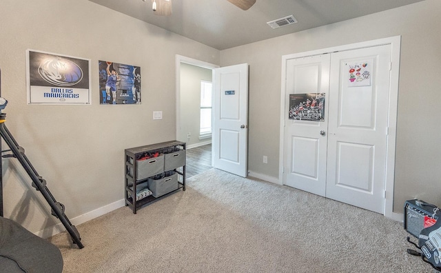 interior space featuring light colored carpet, ceiling fan, and a closet