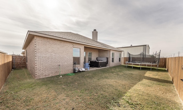 back of property featuring a jacuzzi and a lawn