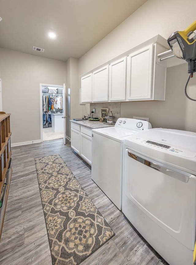 laundry room featuring cabinets, sink, independent washer and dryer, and light hardwood / wood-style floors