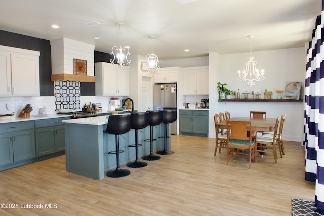 1023 N Fulton Ave, Lubbock, TX 79416 - kitchen featuring a chandelier, backsplash, a kitchen breakfast bar, light wood-style flooring, and freestanding refrigerator