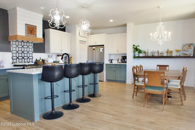 1023 N Fulton Ave, Lubbock, TX 79416 - kitchen featuring a chandelier, recessed lighting, light wood-style floors, tasteful backsplash, and a kitchen island with sink
