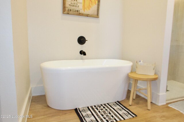 1023 N Fulton Ave, Lubbock, TX 79416 - full bath featuring wood finished floors, a freestanding tub, and baseboards