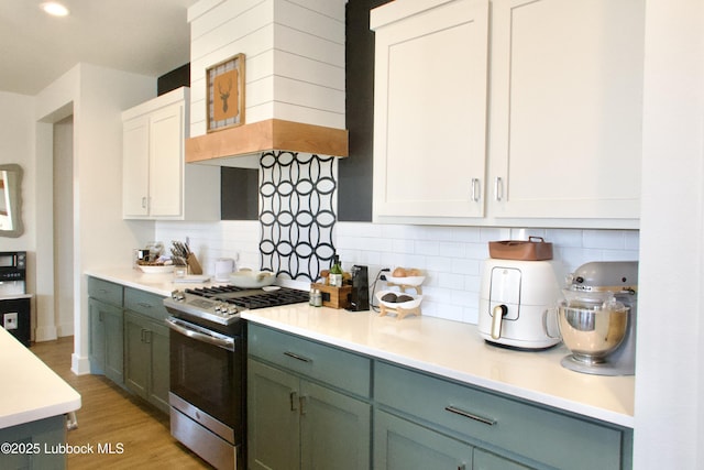 1023 N Fulton Ave, Lubbock, TX 79416 - kitchen with stainless steel gas stove, light countertops, decorative backsplash, light wood-style floors, and white cabinetry