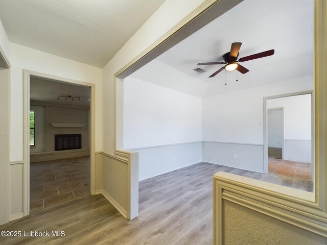 3419 101st St, Lubbock, TX 79423 - unfurnished room with wood finished floors, a ceiling fan, and a large fireplace