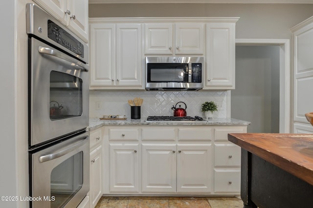 9406 Wayne Ave, Lubbock, TX 79424 - kitchen featuring appliances with stainless steel finishes, decorative backsplash, white cabinetry, and light stone countertops