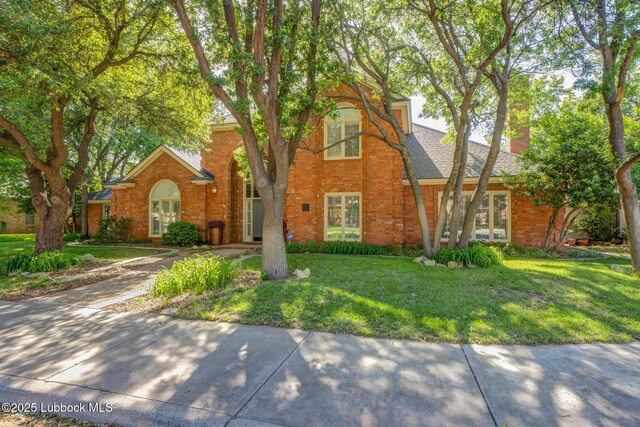 9406 Wayne Ave, Lubbock, TX 79424 - traditional-style home featuring a front yard, brick siding, a chimney, and french doors
