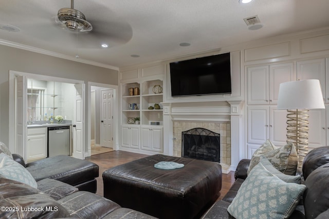9406 Wayne Ave, Lubbock, TX 79424 - living area featuring ceiling fan, crown molding, wood finished floors, a tile fireplace, and built in features