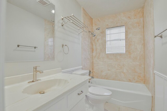 full bathroom with vanity, tiled shower / bath, a textured ceiling, and toilet