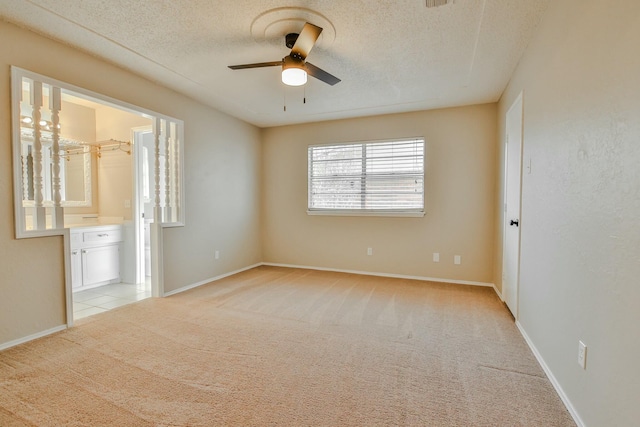 unfurnished bedroom with light carpet, connected bathroom, a textured ceiling, and ceiling fan