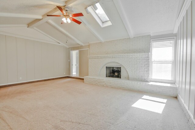 unfurnished living room with ceiling fan, vaulted ceiling with skylight, carpet, a fireplace, and a textured ceiling