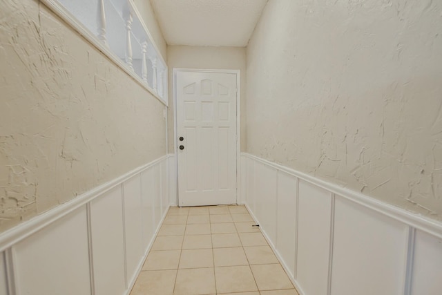 hall featuring light tile patterned floors and a textured ceiling