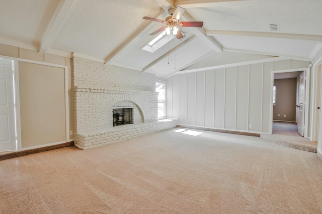 unfurnished living room with ceiling fan, lofted ceiling with skylight, light carpet, and a fireplace