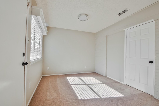 unfurnished bedroom with light carpet and a textured ceiling