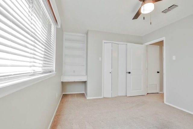 unfurnished bedroom with light colored carpet, ceiling fan, and a closet