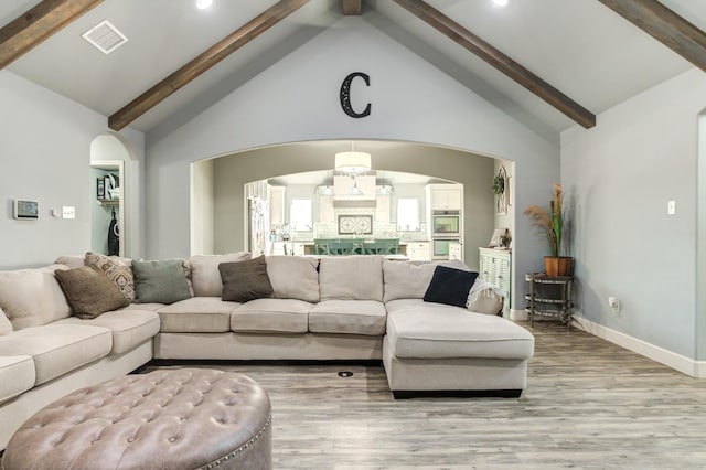 living room with beam ceiling, light hardwood / wood-style floors, and high vaulted ceiling