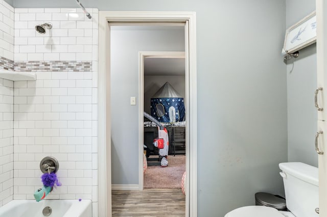 bathroom with tiled shower / bath, wood-type flooring, and toilet