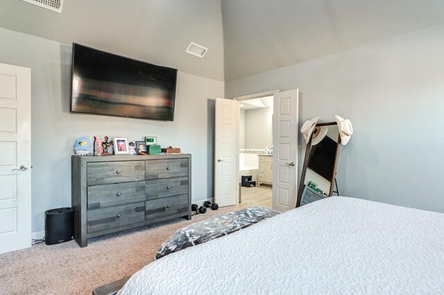 carpeted bedroom with connected bathroom and vaulted ceiling